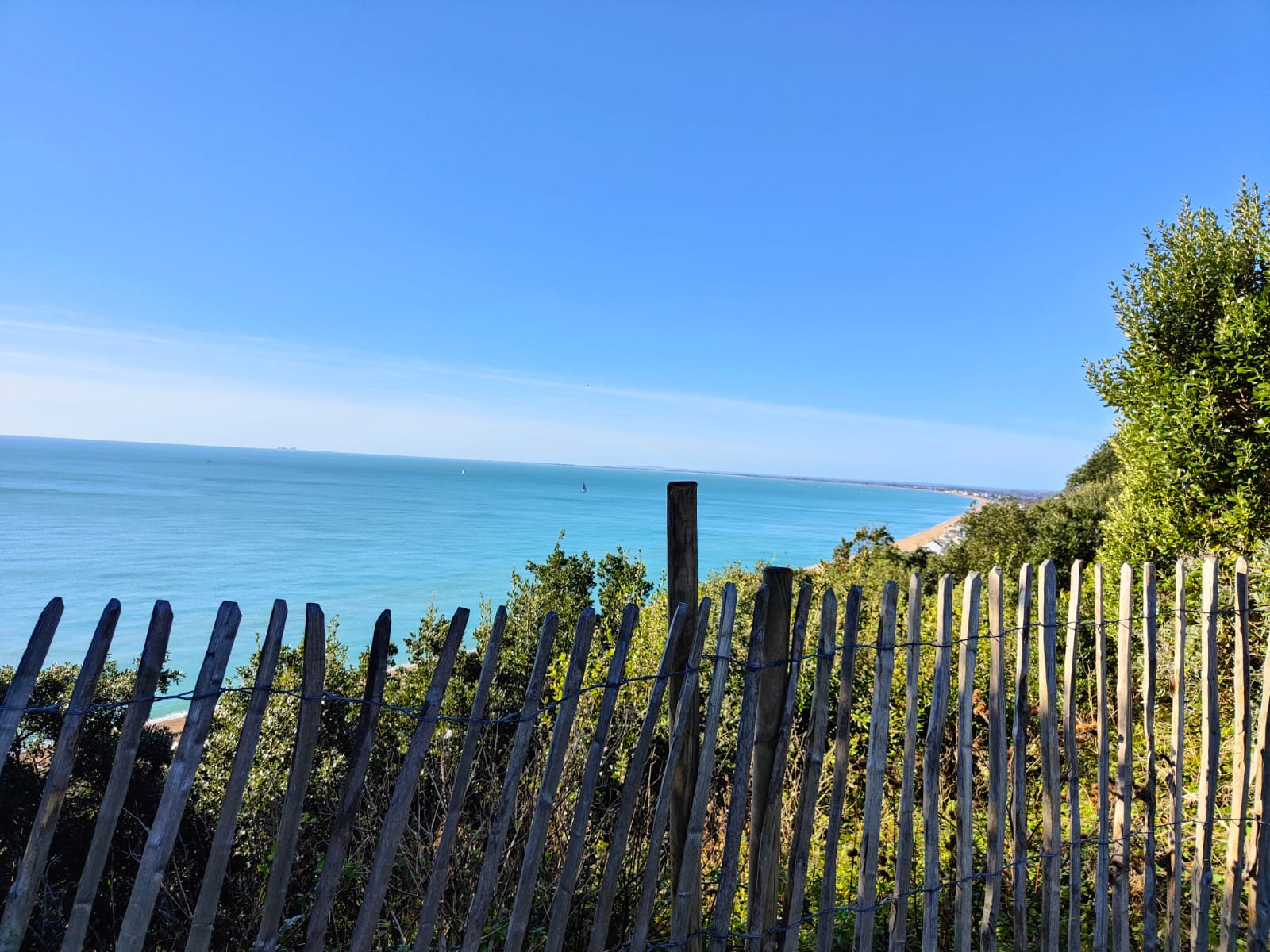 Coastal view over a turquoise sea framed by a wooden fence