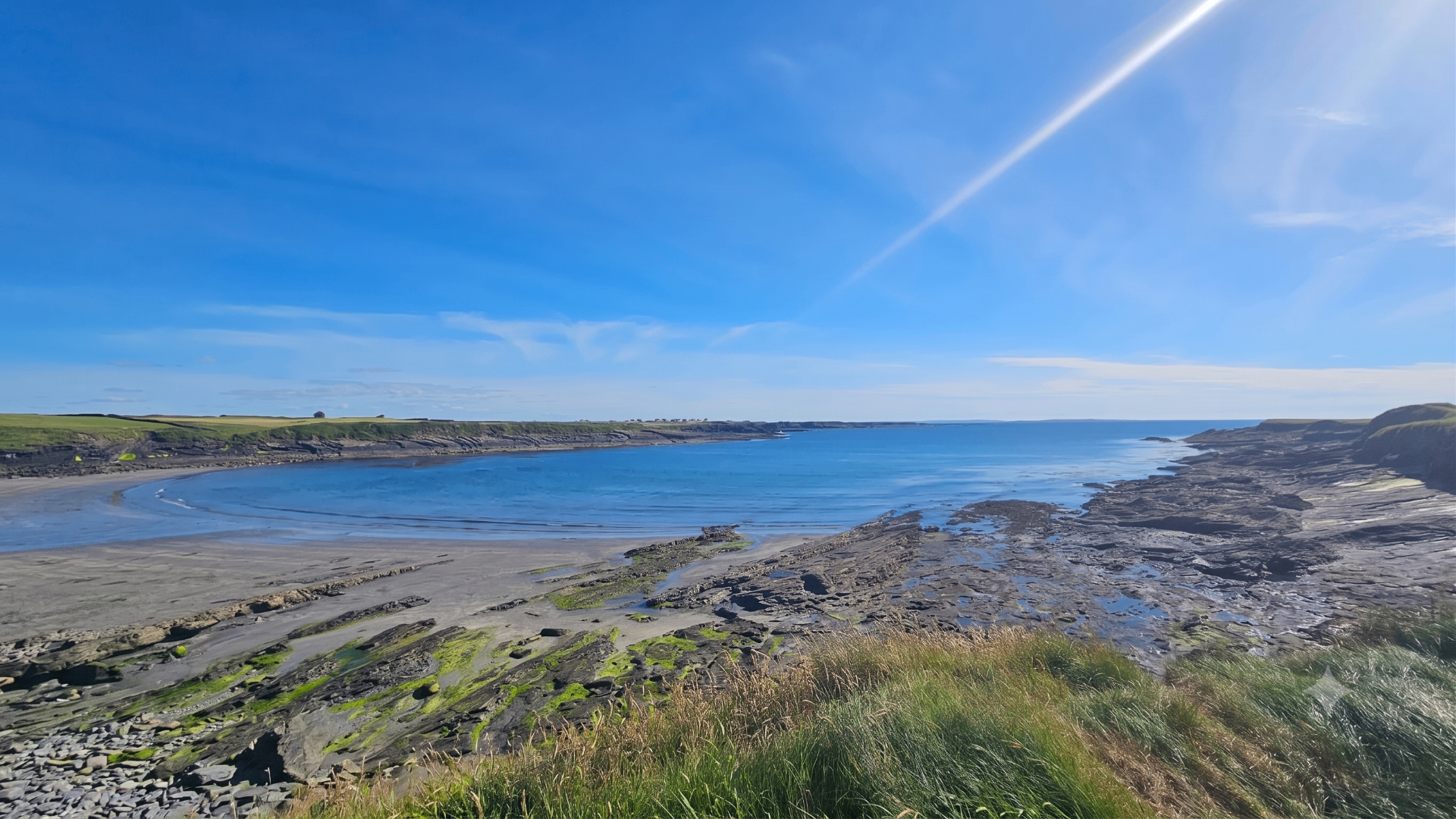 Irish coastal bay under a bright blue sky
